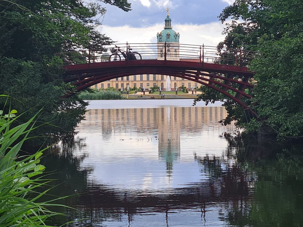 Slot Charlottenburg in Berlijn met op de voorgrond een brug met daarop een fiets. In het water een reflectie van het paleis.